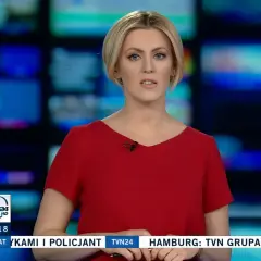 Justyna Kosela, prezenterka w czerwonej sukience, na tle ekranów. Ile ma lat? Tego nie wiemy, ale wygląda profesjonalnie.