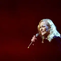 Blondynka śpiewa do mikrofonu, a jej głos niesie ze sobą zapach róży tekst.