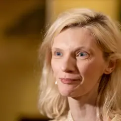 Agata Buzek zamyślona, być może wspominająca swoje dzieci. Jej spojrzenie kieruje się w bok, a na twarzy maluje się delikatny uśmiech.