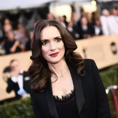 Winona Ryder w czarnej marynarce, z burzą brązowych włosów. Wygląda jakby opowiadała o swoich dzieciach.