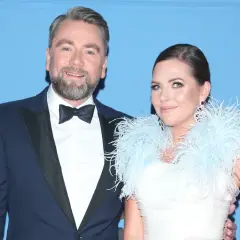 Mąż Oli Kwaśniewskiej, Piotr, w eleganckim garniturze u boku żony w białej sukni z piórami.