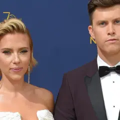 Scarlett Johansson w białej sukni i Colin Jost, jej mąż, w garniturze na czerwonym dywanie.