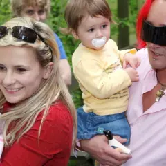 Uśmiechnięta kobieta z dzieckiem na rękach i mężczyzna z rudymi włosami trzymający drugie dziecko. To pola wiśniewska dzieci.