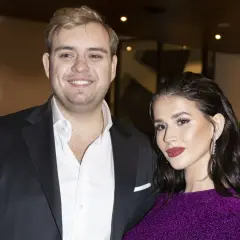 Roksana Węgiel i jej mąż, Kevin Mglej, uśmiechają się do obiektywu. Ona w błyszczącej, fioletowej sukience, on w eleganckim garniturze.