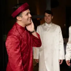 Żaklina i Dinh, mąż, w tradycyjnych strojach. Uśmiechnięty pan młody w czerwonym ao dai, obok niego dwaj panowie w białych.