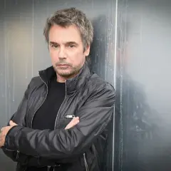 Jean-Michel Jarre, zamyślony, w czarnej kurtce, jakby czekał na swoją żonę.