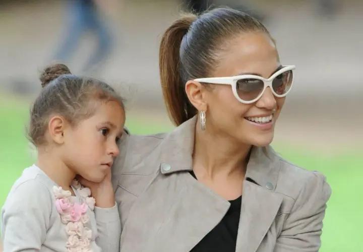 Jennifer Lopez z córką, Emme, w słoneczny dzień. Dziewczynka przytula się do mamy, która uśmiecha się do obiektywu.