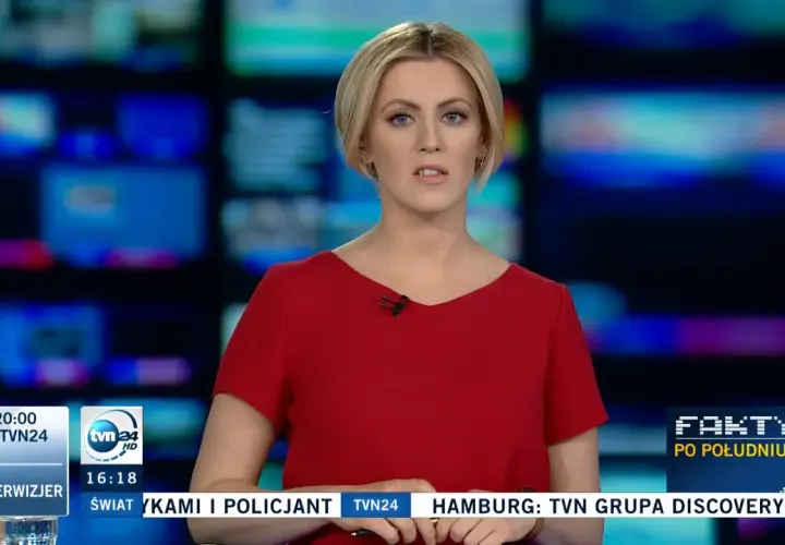 Justyna Kosela, prezenterka w czerwonej sukience, na tle ekranów. Ile ma lat? Tego nie wiemy, ale wygląda profesjonalnie.