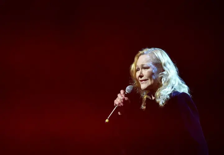 Blondynka śpiewa do mikrofonu, a jej głos niesie ze sobą zapach róży tekst.