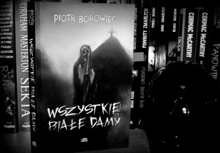 Okładka książki "Wszystkie białe damy" Piotra Borowca. Na okładce widnieje przerażająca postać i krzyż na kopcu.