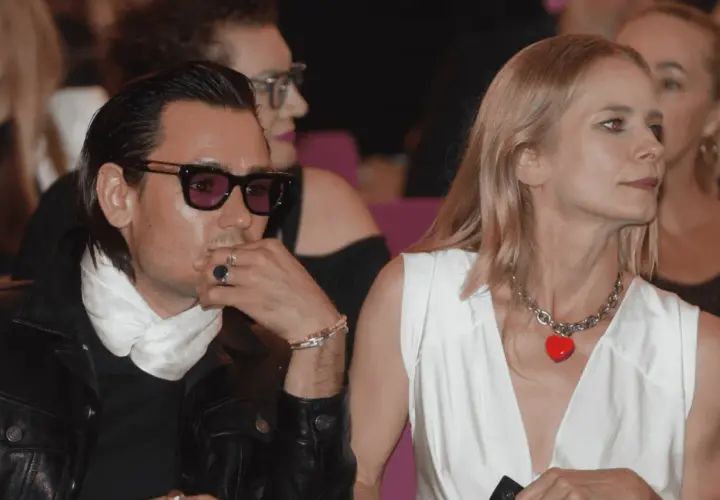 Magdalena Cielecka i Bartosz Gelner na widowni. Ona w białej sukni z naszyjnikiem w kształcie serca, on w skórzanej kurtce i okularach.
