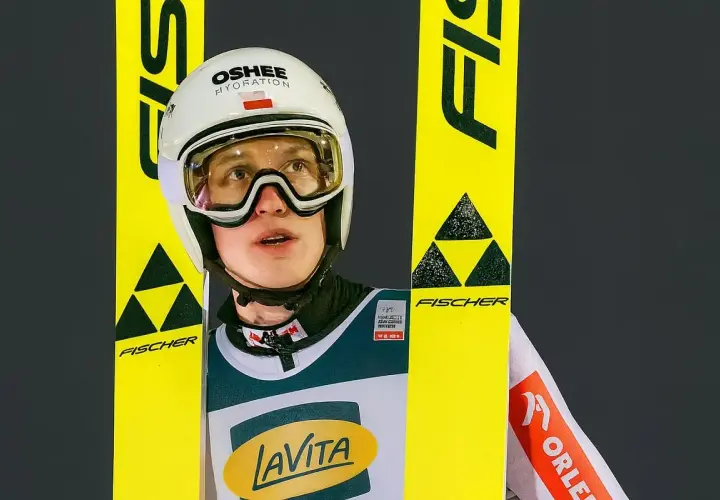Kacper Tomasiak wzrost – młody skoczek narciarski w kasku i goglach, otoczony żółtymi nartami Fischer.