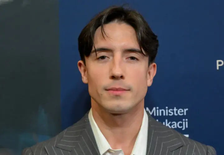 Dawid Kwiatkowski w szarym garniturze. Jego wzrost jest imponujący, a spojrzenie przyciąga uwagę.