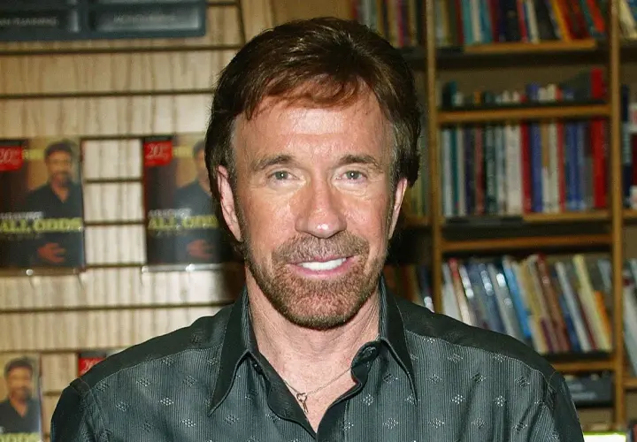 Chuck Norris, którego wiek nie ma znaczenia, bo jest niezniszczalny, pozuje na tle swoich książek.