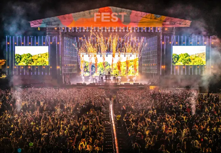 Ogromny tłum na fest festiwalu, scena rozświetlona fajerwerkami i ekranami.