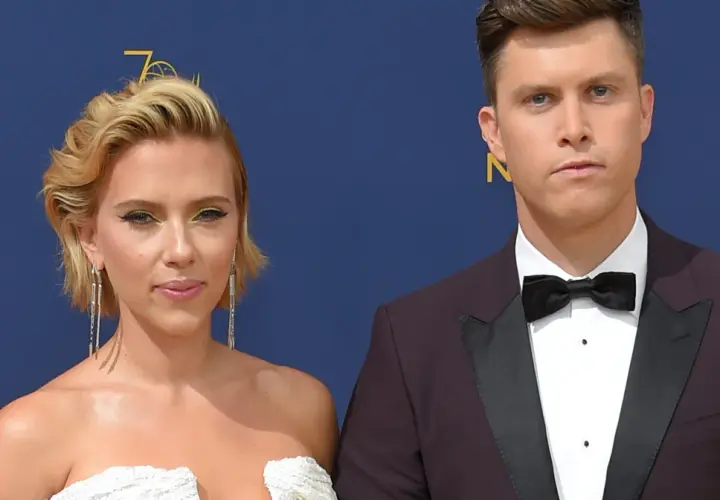Scarlett Johansson w białej sukni i Colin Jost, jej mąż, w garniturze na czerwonym dywanie.