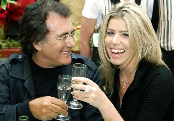 Al Bano i jego nowa partnerka, uśmiechnięci, wznoszą toasty kieliszkami szampana.