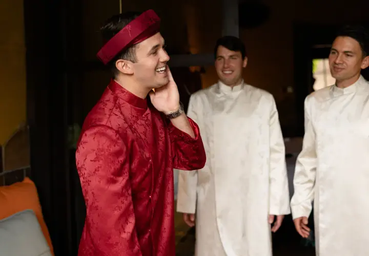 Żaklina i Dinh, mąż, w tradycyjnych strojach. Uśmiechnięty pan młody w czerwonym ao dai, obok niego dwaj panowie w białych.