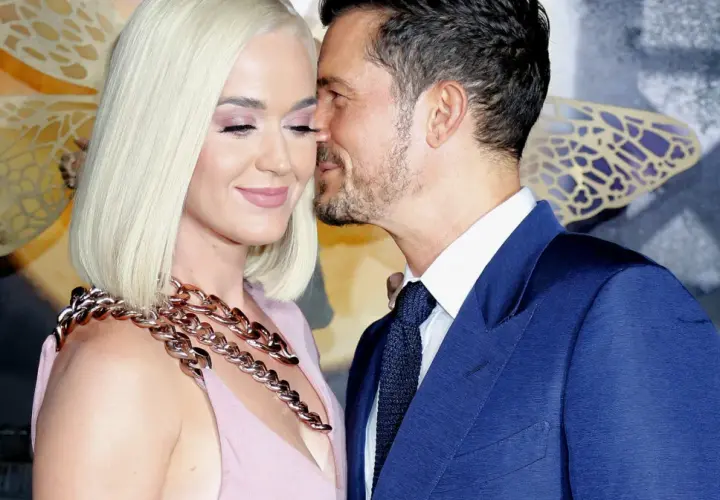 Katy Perry i Orlando Bloom w czułym uścisku. Ona w różowej sukni i masywnym naszyjniku, on w granatowym garniturze.