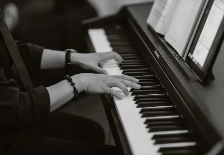 Dłonie grające na pianinie, w eleganckim stroju, tworzą niepowtarzalny styl w jazie.