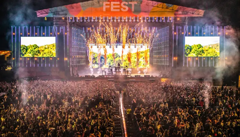 Ogromny tłum na fest festiwalu, scena rozświetlona fajerwerkami i ekranami.