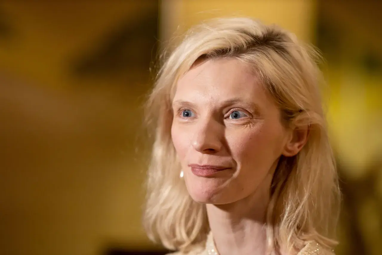 Agata Buzek zamyślona, być może wspominająca swoje dzieci. Jej spojrzenie kieruje się w bok, a na twarzy maluje się delikatny uśmiech.