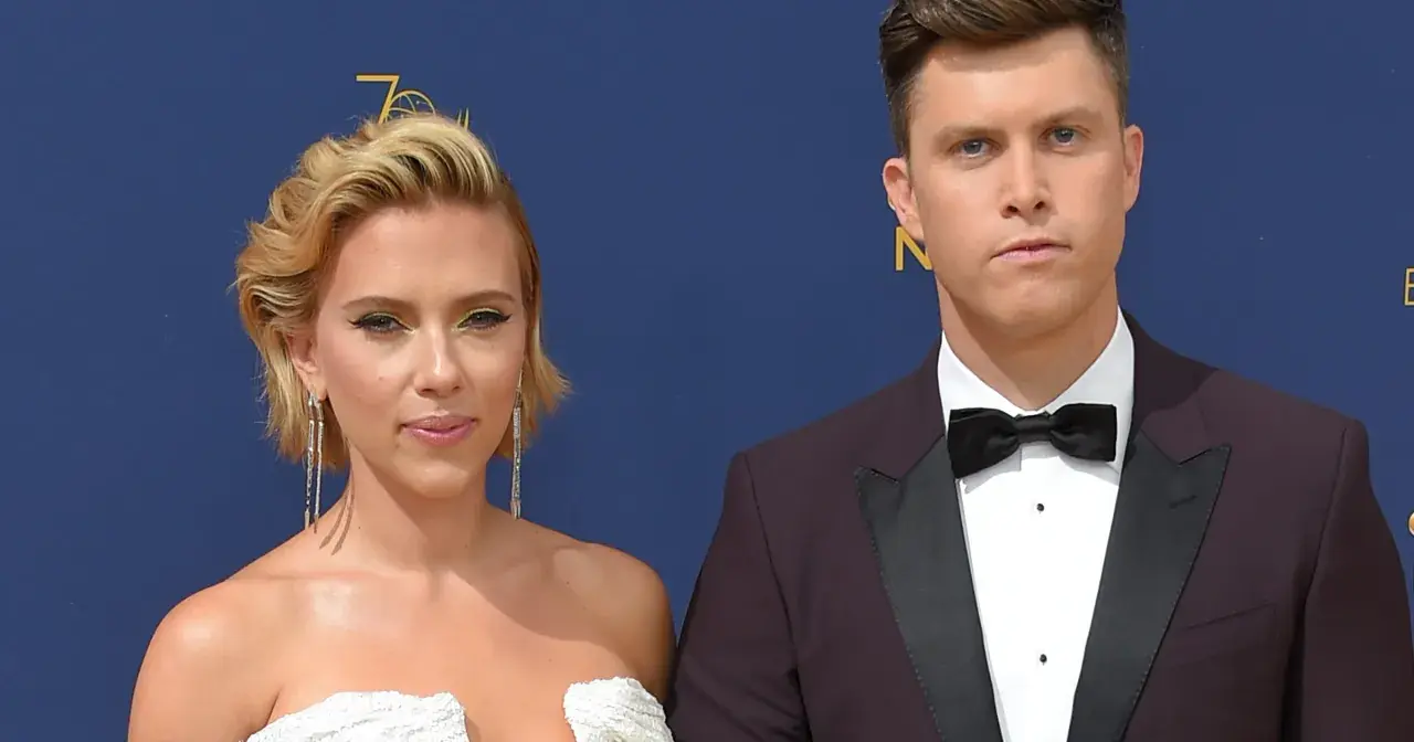 Scarlett Johansson w białej sukni i Colin Jost, jej mąż, w garniturze na czerwonym dywanie.
