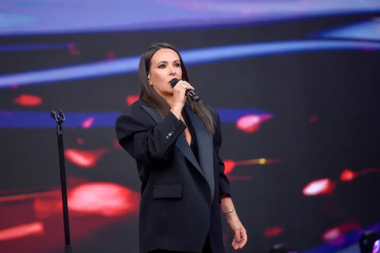 Kasia Kowalska śpiewa na scenie, wykonując swoje utwory w eleganckiej czarnej marynarce.