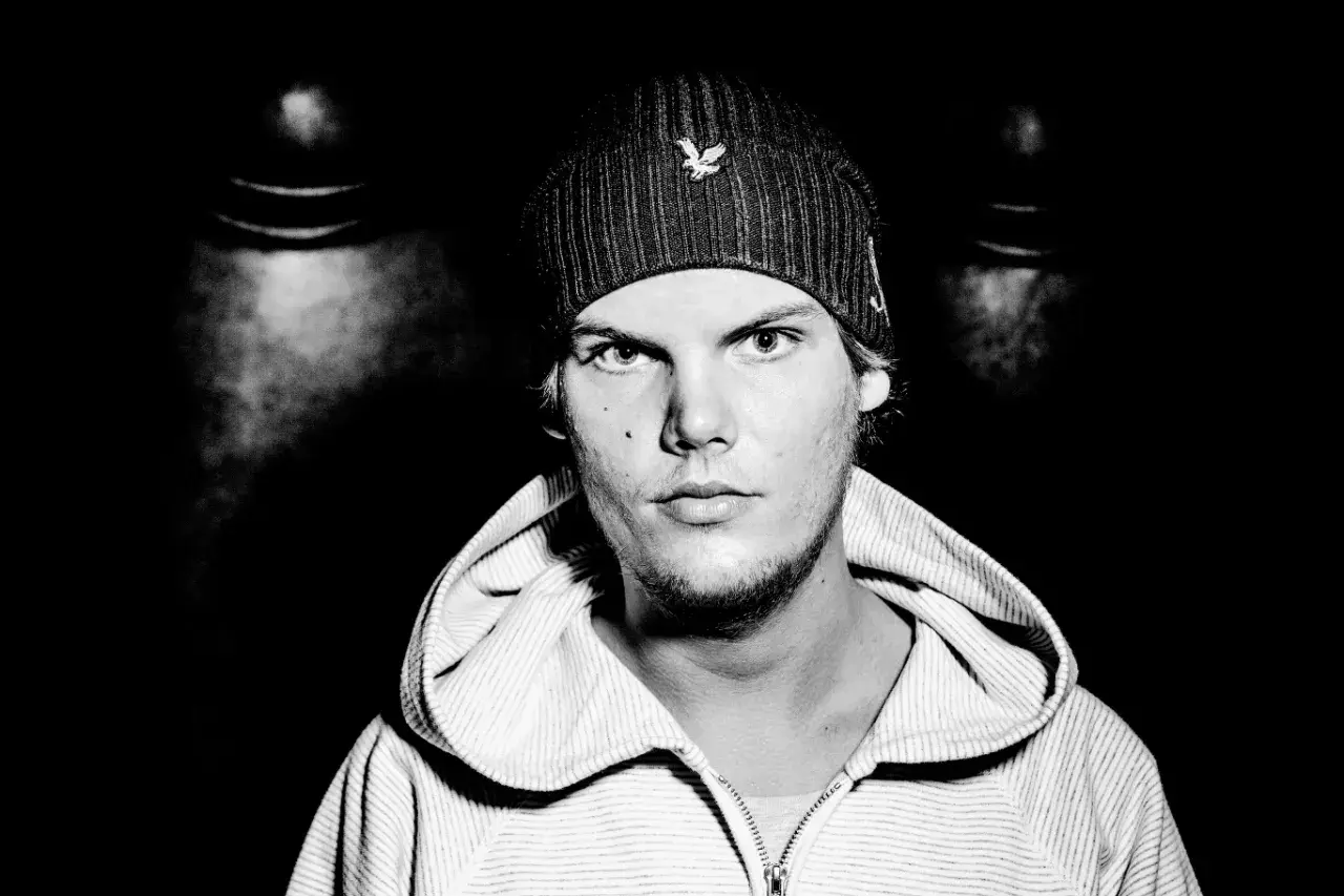 Avicii, młody mężczyzna w czapce z daszkiem i bluzie z kapturem, patrzy prosto w obiektyw.