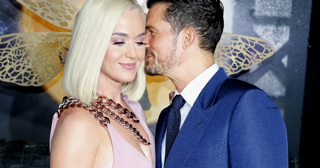 Katy Perry i Orlando Bloom w czułym uścisku. Ona w różowej sukni i masywnym naszyjniku, on w granatowym garniturze.