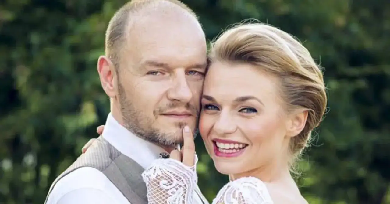 Emilia Komarnicka i jej pierwszy mąż, Tomasz, w dniu ślubu. Uśmiechnięta para na tle zieleni.