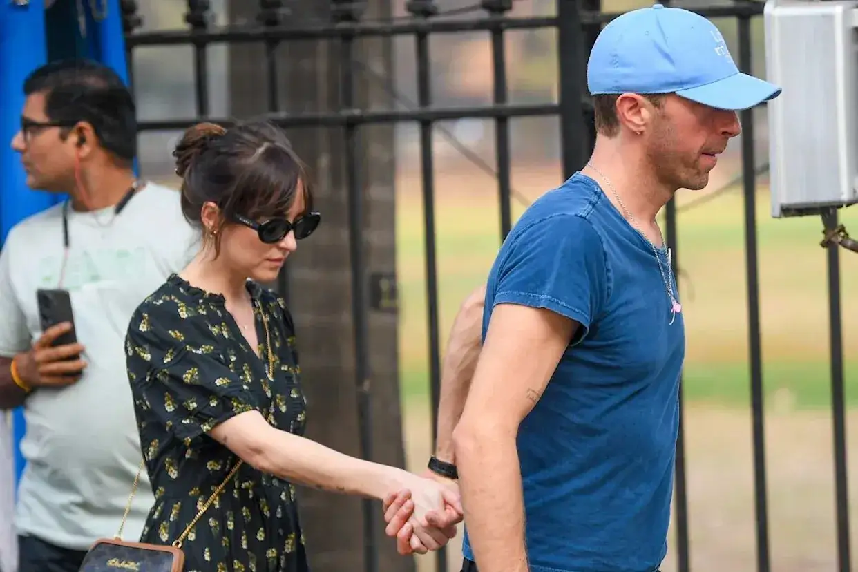 Dakota Johnson i Chris Martin trzymają się za ręce, idąc ulicą.