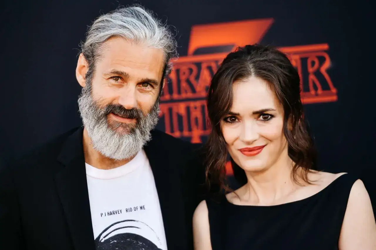 Winona Ryder z mężem, w tle logo Stranger Things.