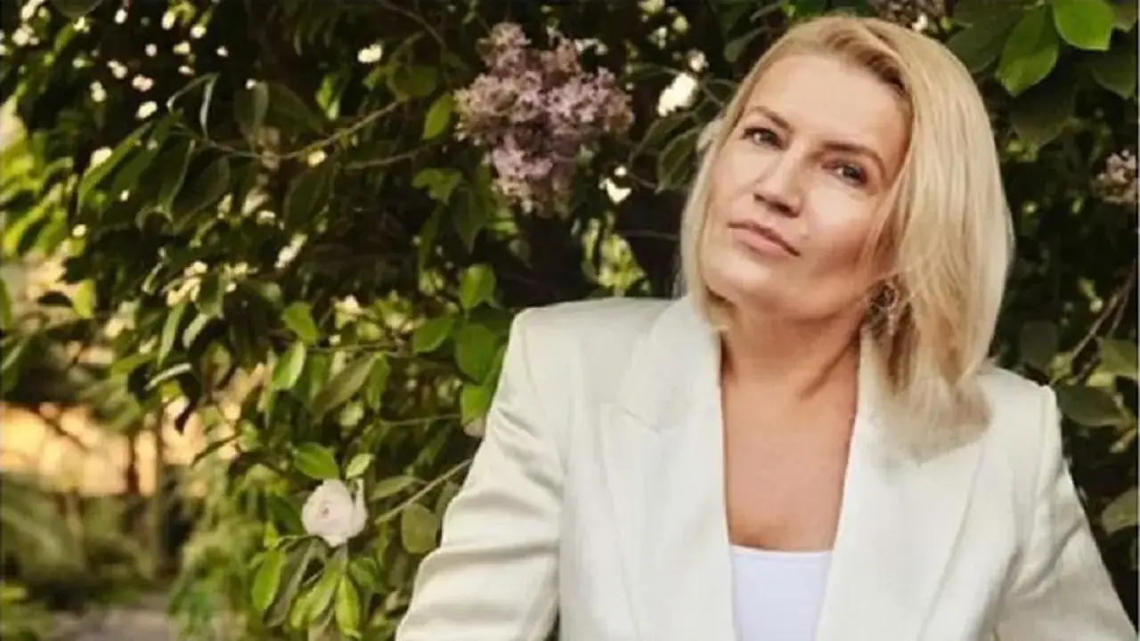 Beata Lubecka, wiek nieznany, w białej marynarce na tle zieleni i kwitnących krzewów.