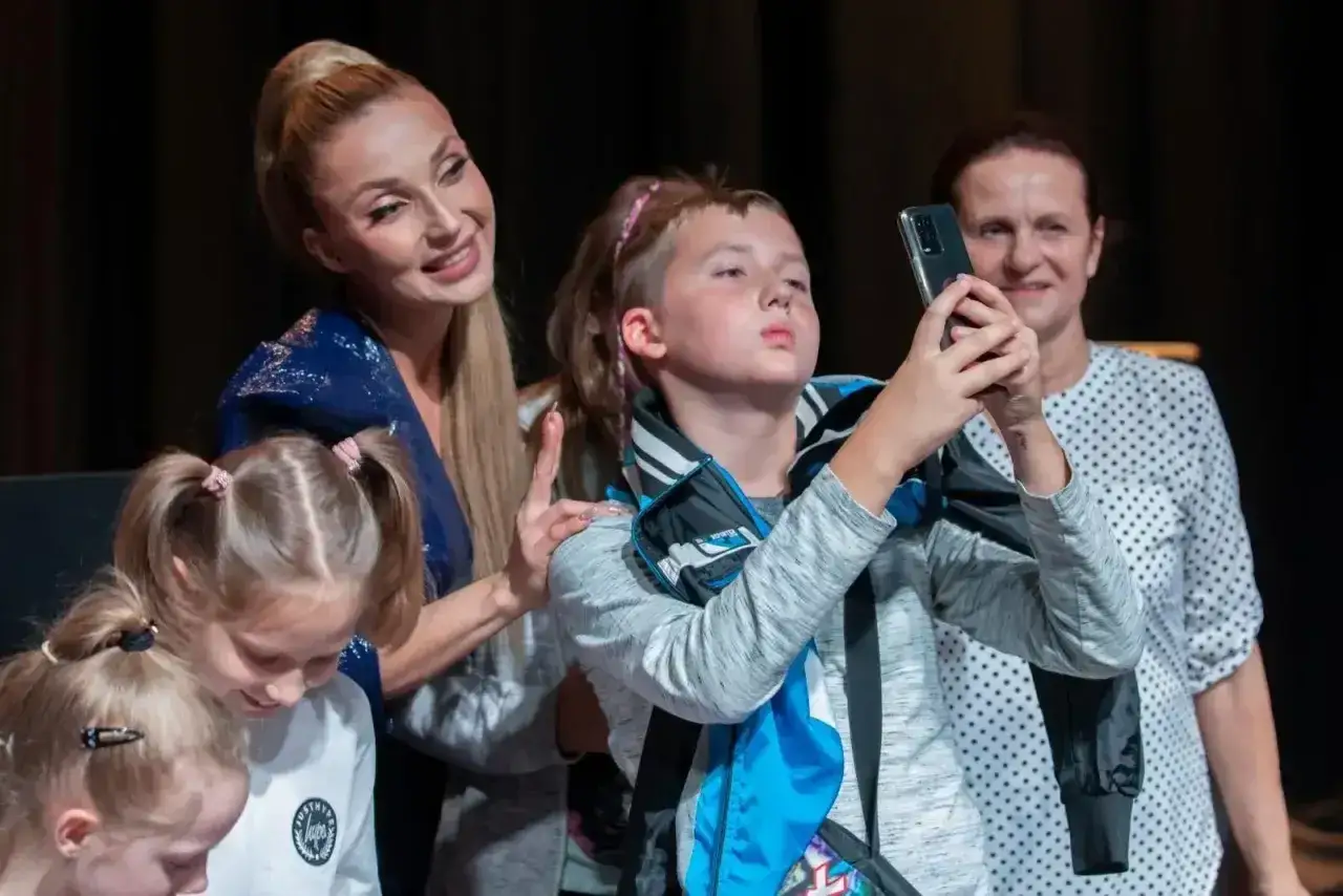Cleo z dziećmi robi sobie selfie. Widać dwie dziewczynki i chłopca, który trzyma telefon.