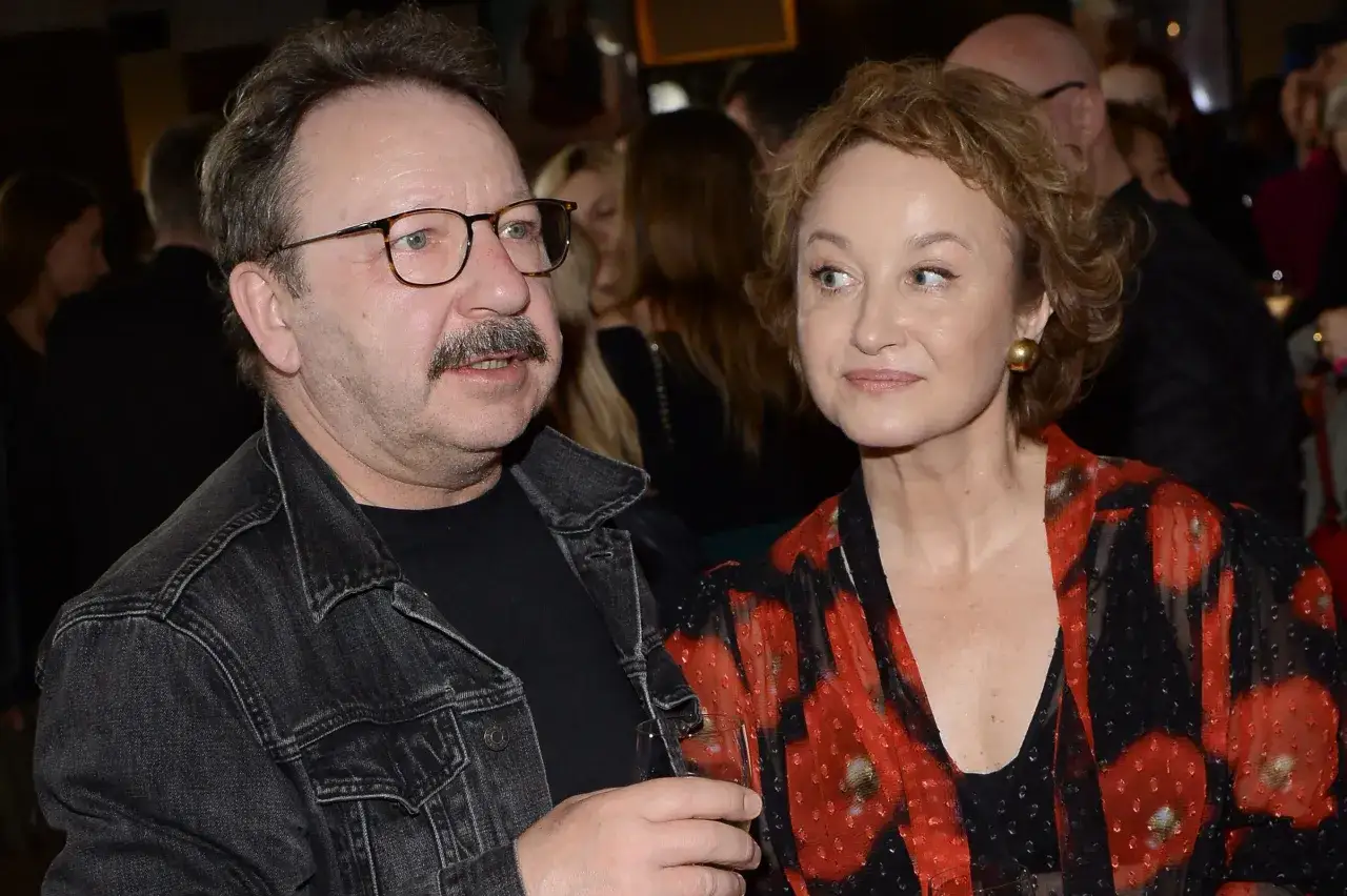 Zbliżenie na Andrzeja Zamachowskiego i jego partnerkę, uśmiechniętą kobietę w sukience w czerwone maki.